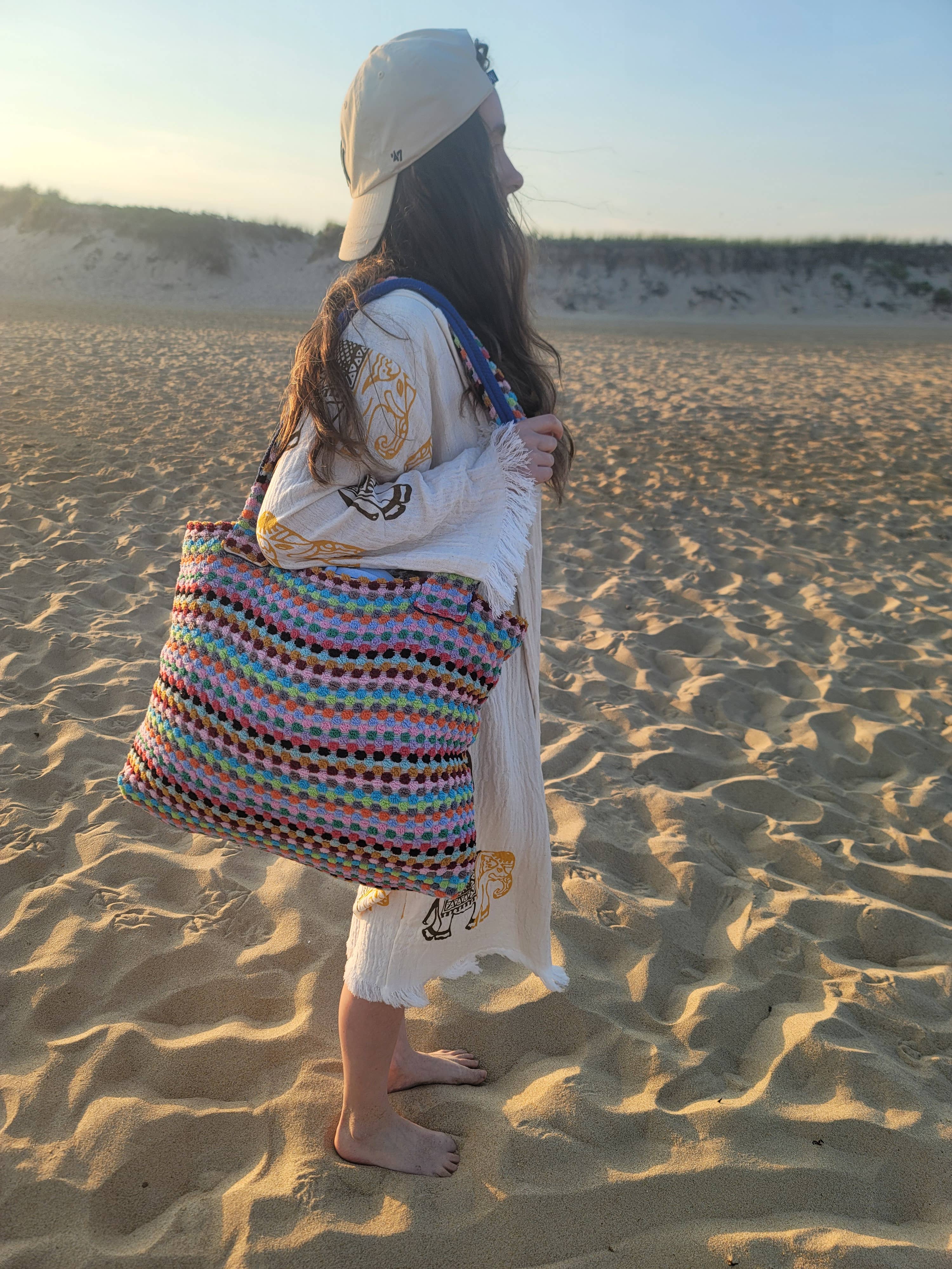 Person holding a colorful bag on a sandy beach
