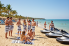 Group of people on a beach with jet skis and palm trees in the background