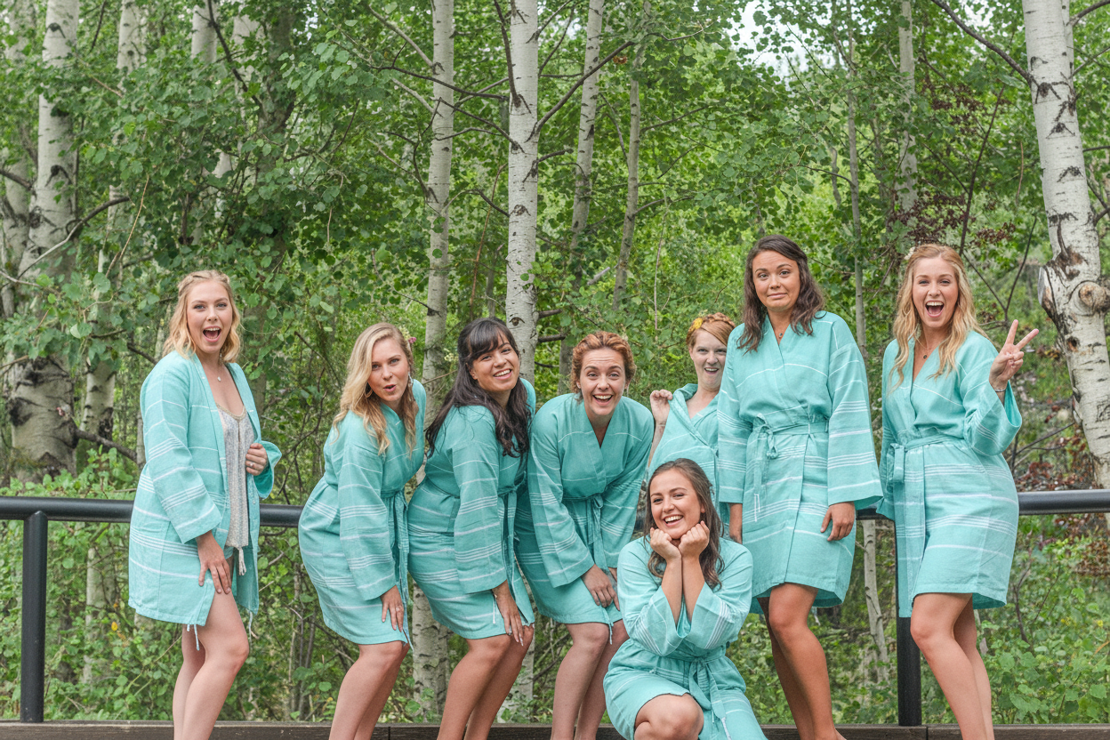 Group of women in matching teal robes posing outdoors with trees in the background